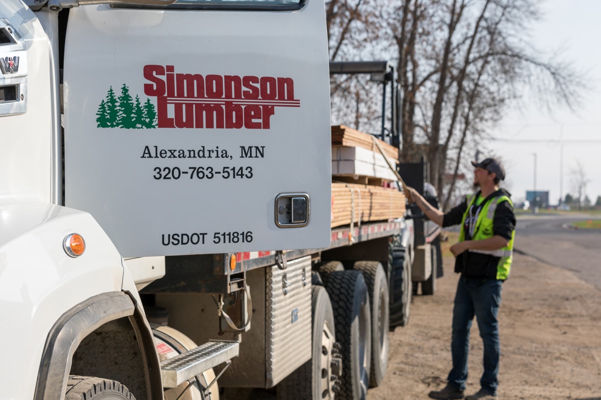 man standing next to a simonsons lumber truck
